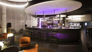 A modern bar area with a curved counter, bar stools, and ambient lighting. - Novotel Basel City (Basel)