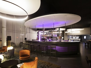 A modern bar area with a curved counter, bar stools, and ambient lighting.
