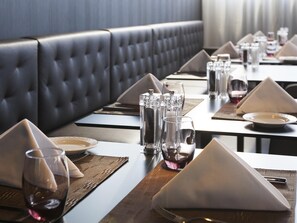 Un restaurante con una mesa larga, elegantemente servida con platos, vasos y cubiertos.