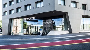 A modern hotel building with a prominent 'NOVOTEL' sign, multiple floors, and a ground-level entrance. - Novotel Basel City (Basel)
