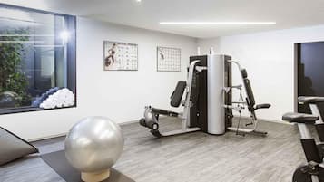 Un gimnasio moderno con equipo de ejercicio, una pelota de ejercicio grande y un ventanal con vistas a la vegetación.