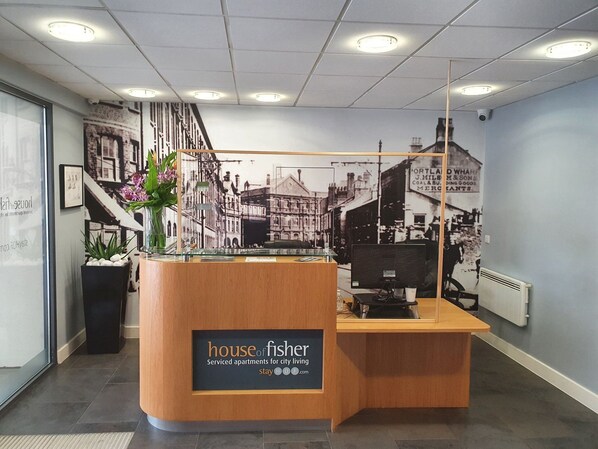 Una recepción con un cartel que dice "house of fisher serviced apartments for city living".