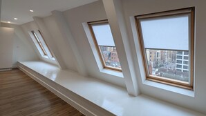 Een kamer met een schuine kap, dakramen, houten vloeren en een lange bank langs de muur.