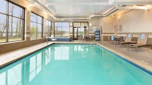 An indoor swimming pool with clear windows, a sunlit area with chairs and tables, and a view of trees outside. - Country Inn & Suites by Radisson, Bemidji, MN (Bemidji)