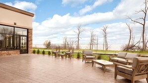 An outdoor patio with wooden furniture, a stone floor, and a view of a lake and trees. - Country Inn & Suites by Radisson, Bemidji, MN (Bemidji)