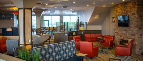 A spacious lobby with a mix of seating options, including sofas and chairs, a fireplace, and a large window providing natural light.