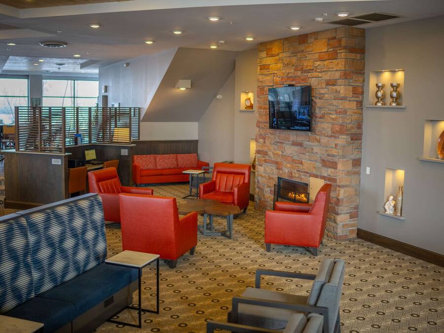 A modern lounge area with red seating, a stone fireplace, and a large TV screen.
