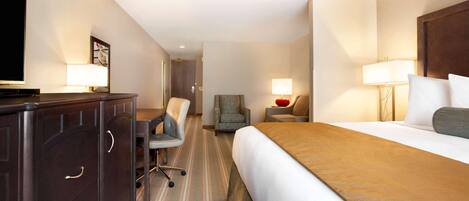 A hotel room with a bed, a desk with a chair, a TV, and two bedside lamps.