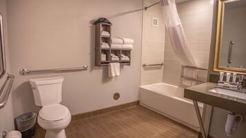 Un baño con inodoro, bañera, ducha con cortina, toallero y espejo.