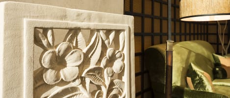 A carved floral design on a wall, a lamp, and a green upholstered chair.