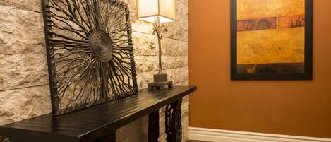 A stone wall with a decorative metal piece and a framed painting.