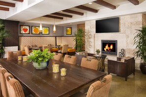 Amplia sala de estar con una gran mesa de madera, asientos cómodos, chimenea y plantas decorativas.