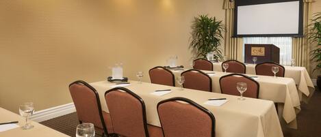 A conference room with multiple tables, chairs, and a projector screen.