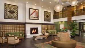 A spacious lobby with a fireplace, seating area, and decorative wall panels. - Ayres Hotel Orange (Orange)