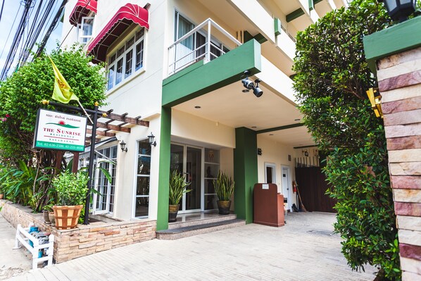 A hotel entrance with a sign, potted plants, and a wooden deck. - The Sunrise Residence (Bangkok)