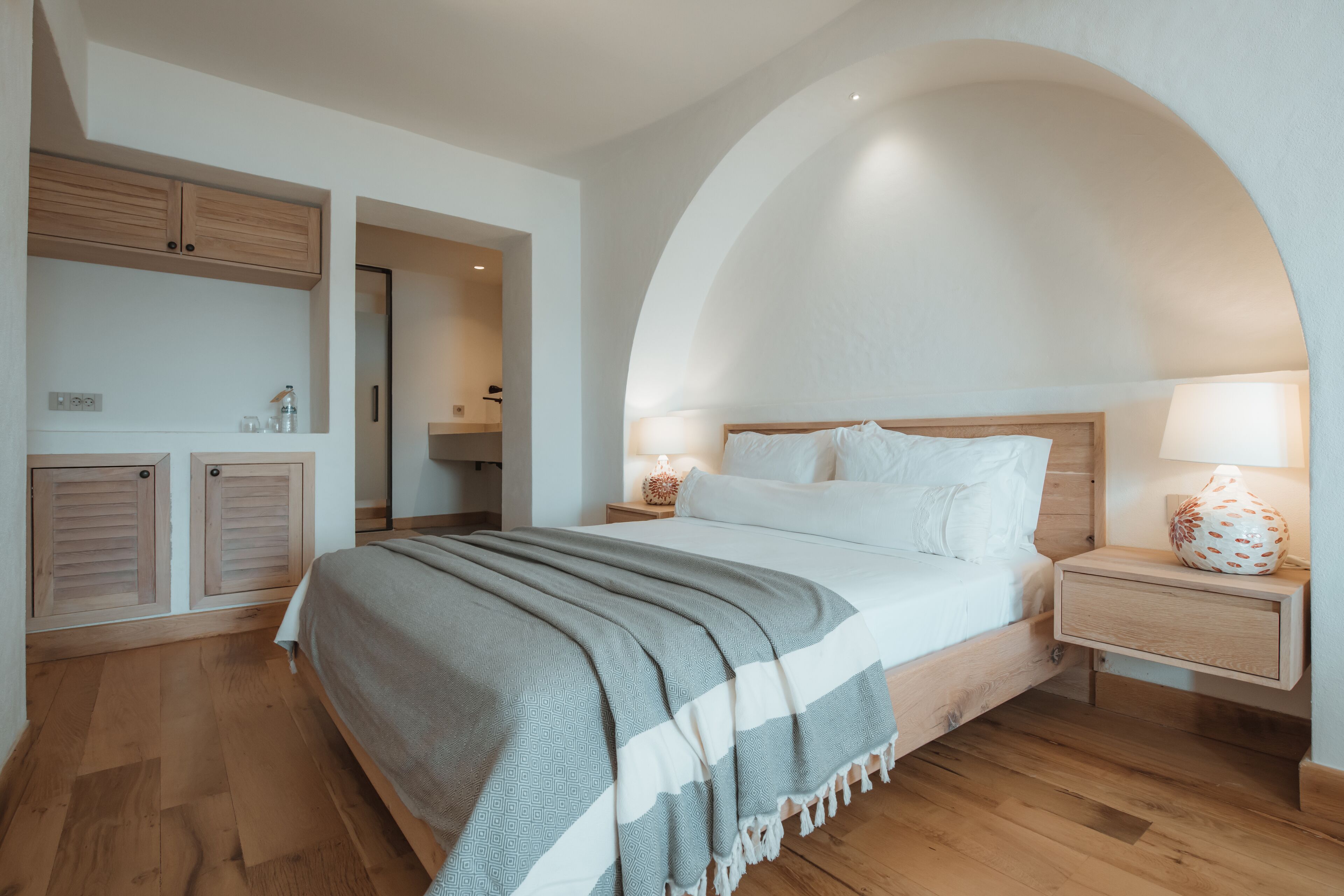 A bedroom with a bed, bedside tables, a lamp, and a wooden cabinet.