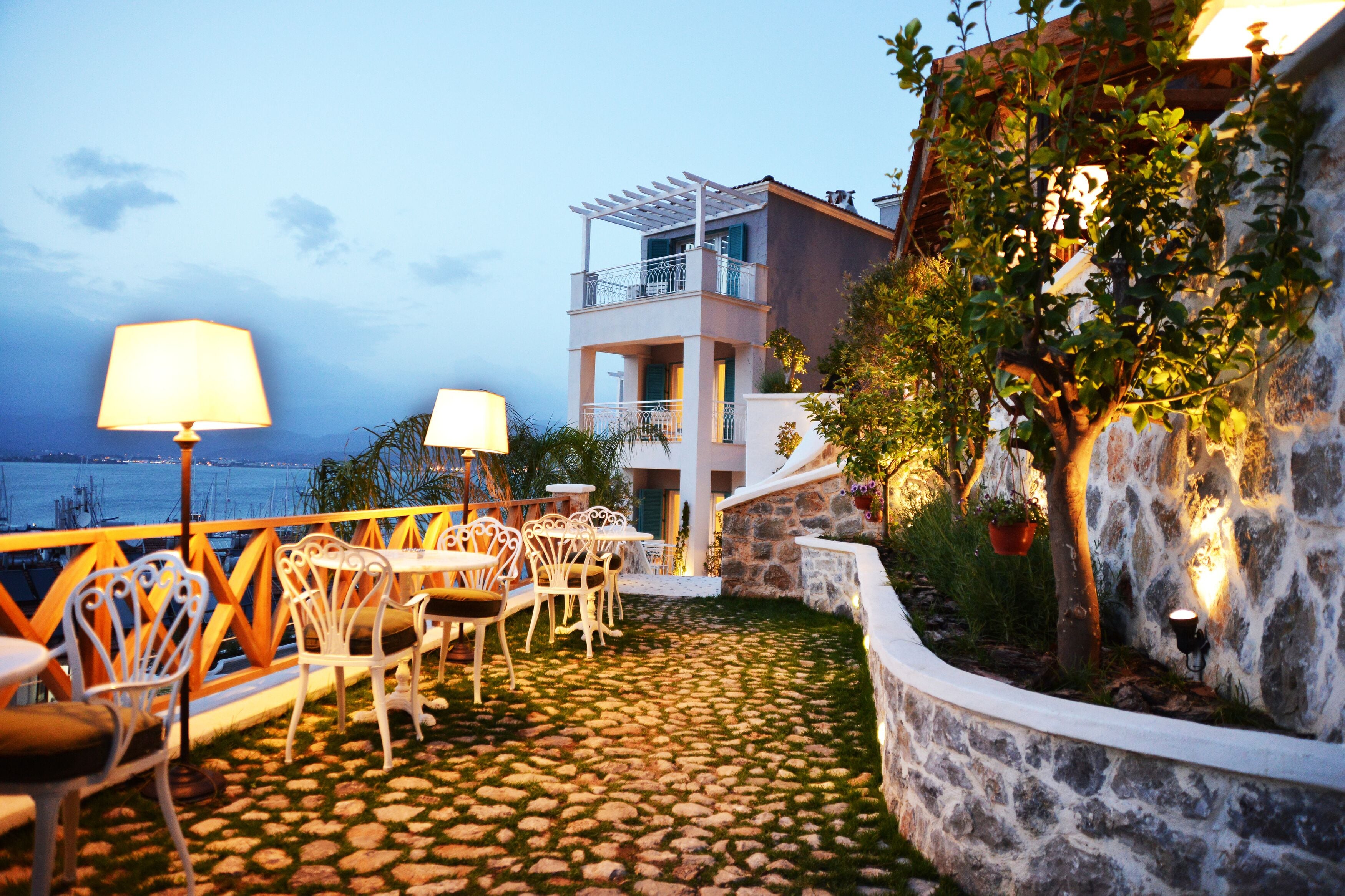 Una terraza con suelo de piedra, mobiliario exterior y vista al mar.