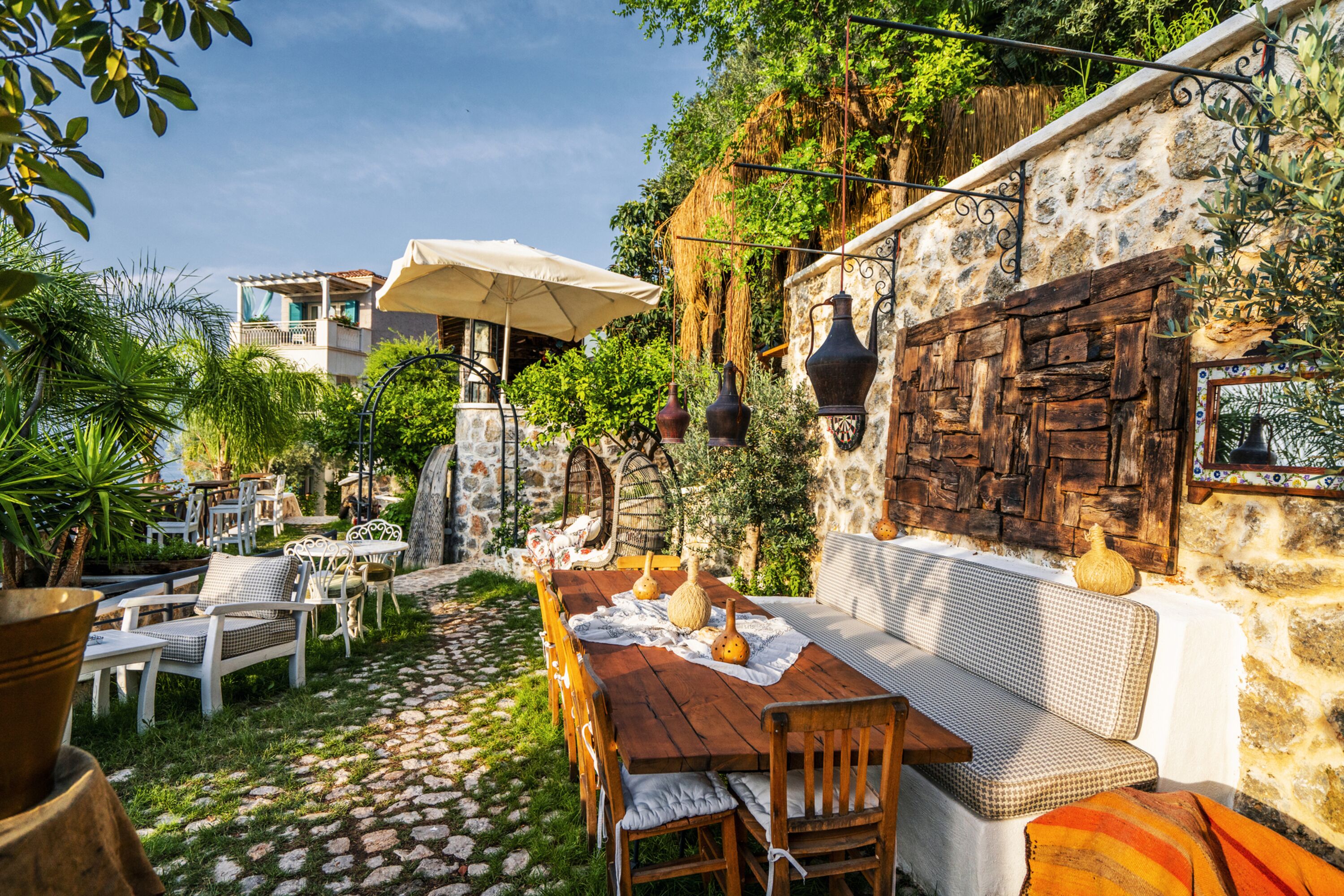 An outdoor patio with stone walls, wooden furniture, and a stone table.