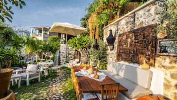 An outdoor patio with stone walls, wooden furniture, and a stone table.