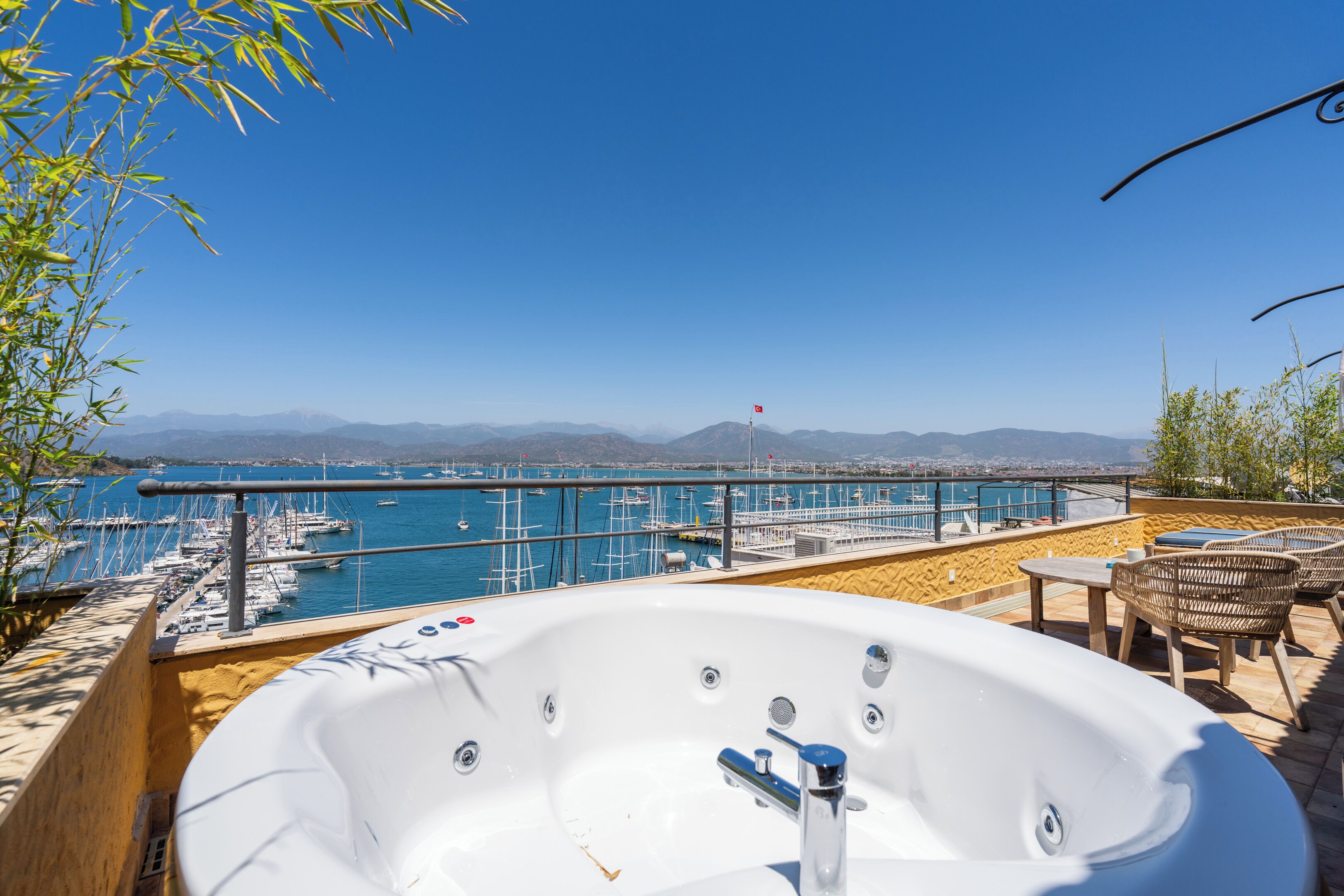 Uma banheira de hidromassagem com vista para um porto e montanhas.