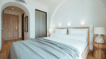 Un dormitorio con una cama, una puerta de madera, un espejo y una lámpara.