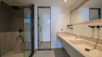 A modern bathroom with a glass shower enclosure, a large mirror, and a beige countertop with two sinks.