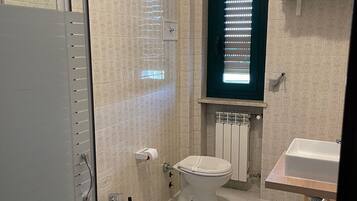 Un baño con ducha, inodoro, bidé y lavamanos.