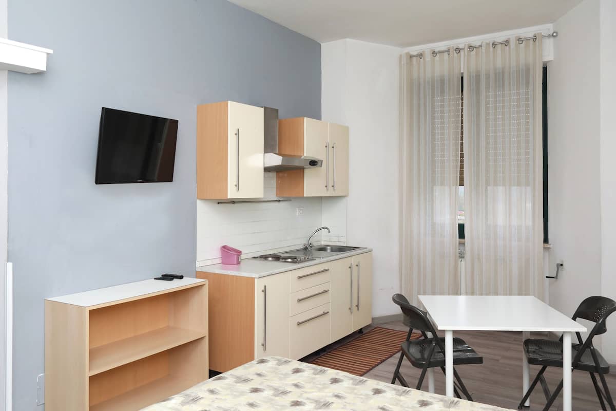 A compact kitchen with a sink, cabinets, and a dining area with chairs.