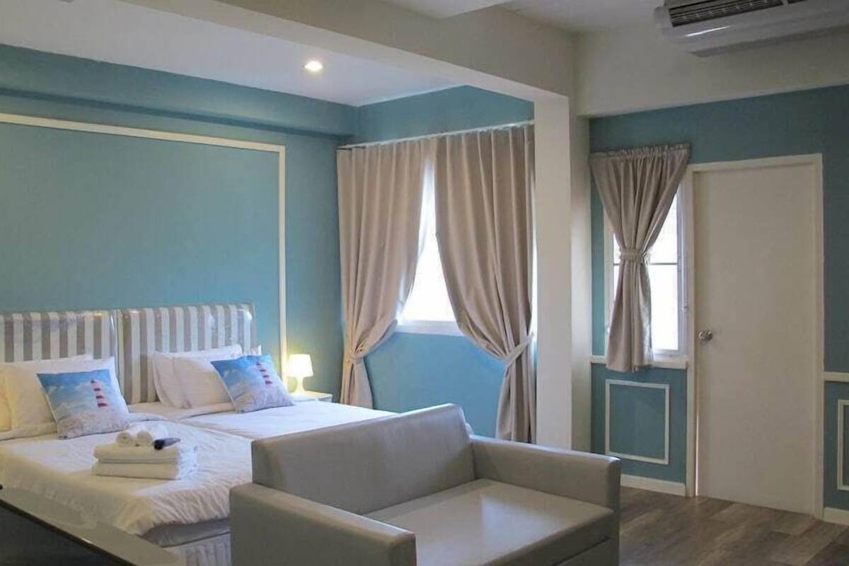 A bedroom with a bed, bedside tables, a sofa, and a window with curtains.
