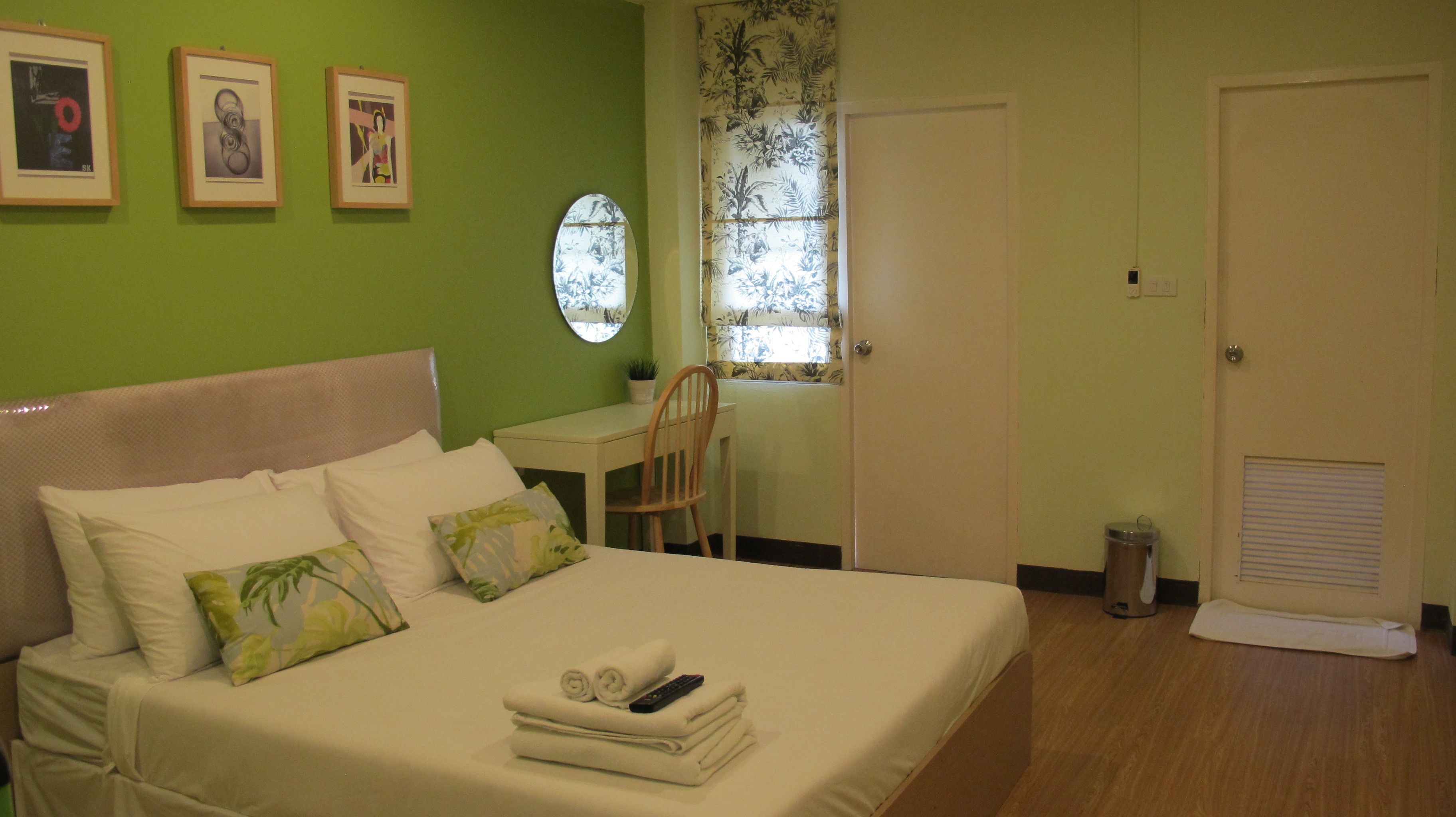A bedroom with a bed, a desk, and a chair. There are three framed pictures on the wall.