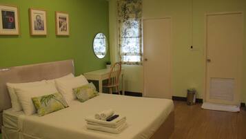 A bedroom with a bed, a desk, and a chair. There are three framed pictures on the wall.