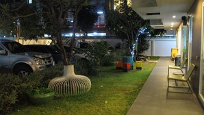 A well-maintained outdoor area with a pathway leading to a seating area, surrounded by greenery and modern outdoor furniture. - U431 Chaengwattana (Pak Kret)