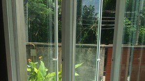 A modern room with a large glass window, a sofa with cushions, and a view of a garden. - U431 Chaengwattana (Pak Kret)