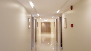 A modern, well-lit hallway with doors on both sides, leading to a room at the end. - Florida Hotel (Bangkok)