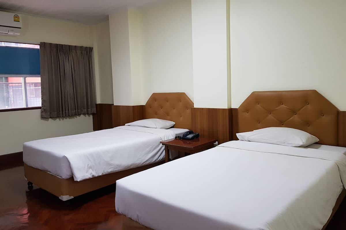 Habitación de hotel con dos camas individuales, cabecero de madera, mesita de noche con teléfono y ventana con cortinas.