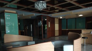 A modern lobby with curved seating, a chandelier, and a reception desk. - Florida Hotel (Bangkok)