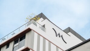 Un edificio moderno con un diseño minimalista, que presenta un llamativo logotipo 'M' en la fachada.
