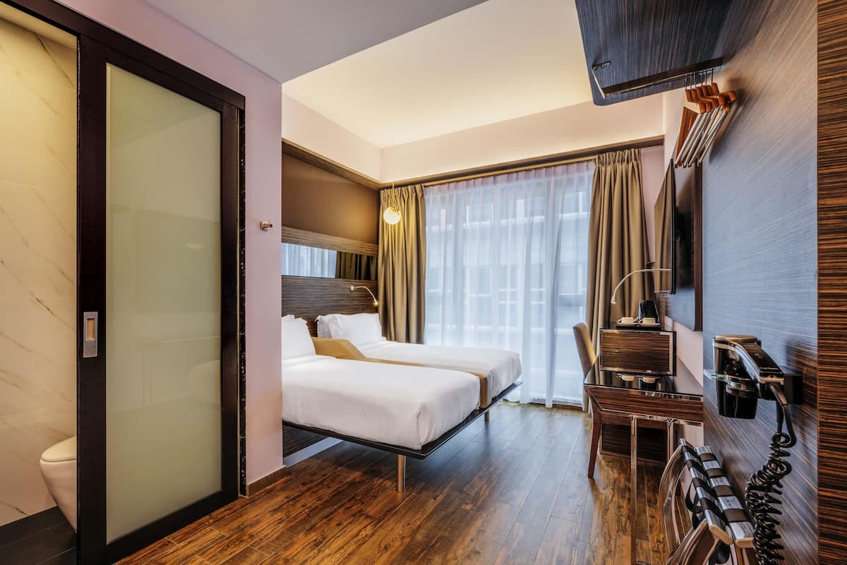 Une chambre d’hôtel équipée d’un lit, d’un bureau, d’une chaise, d’un téléphone et d’une télévision.