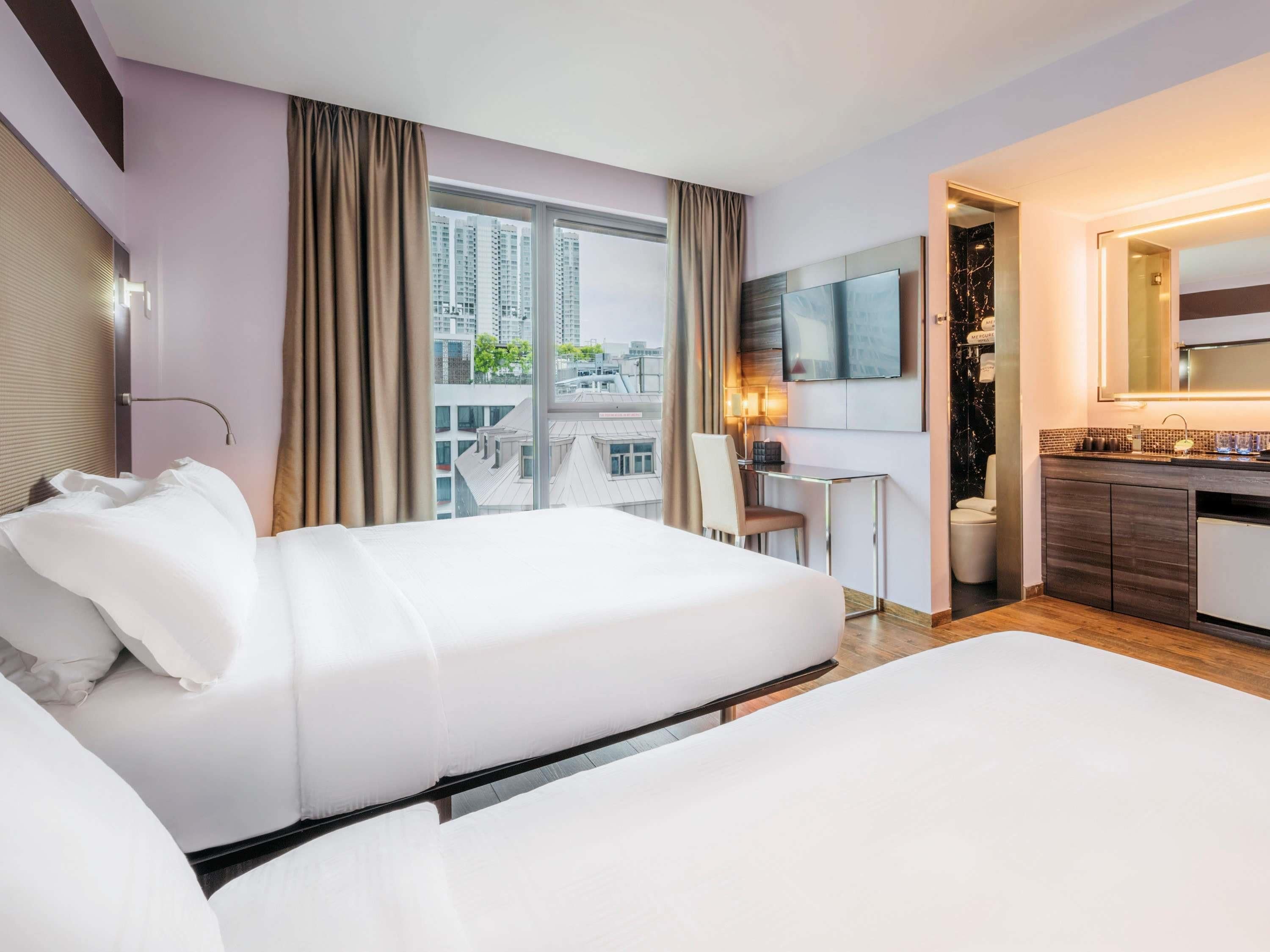 Habitación de hotel con dos camas, un escritorio, televisor y baño.