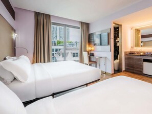 Une chambre d’hôtel avec deux lits, un bureau, une télévision et une salle de bain.