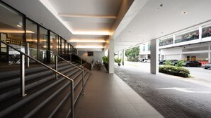 Un pasillo moderno de hotel con una escalera, un área de estar y vistas a la calle.