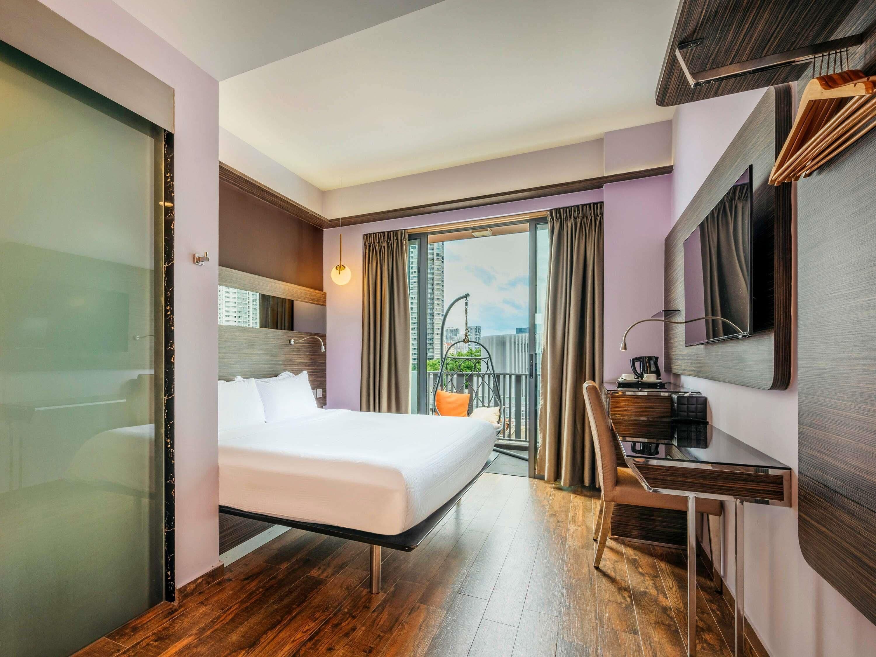 Habitación de hotel con cama, escritorio y vista a la ciudad.