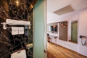 A hotel bathroom with a black marble wall, a sink, and a towel rack with 'Mercure Hotels' towels.