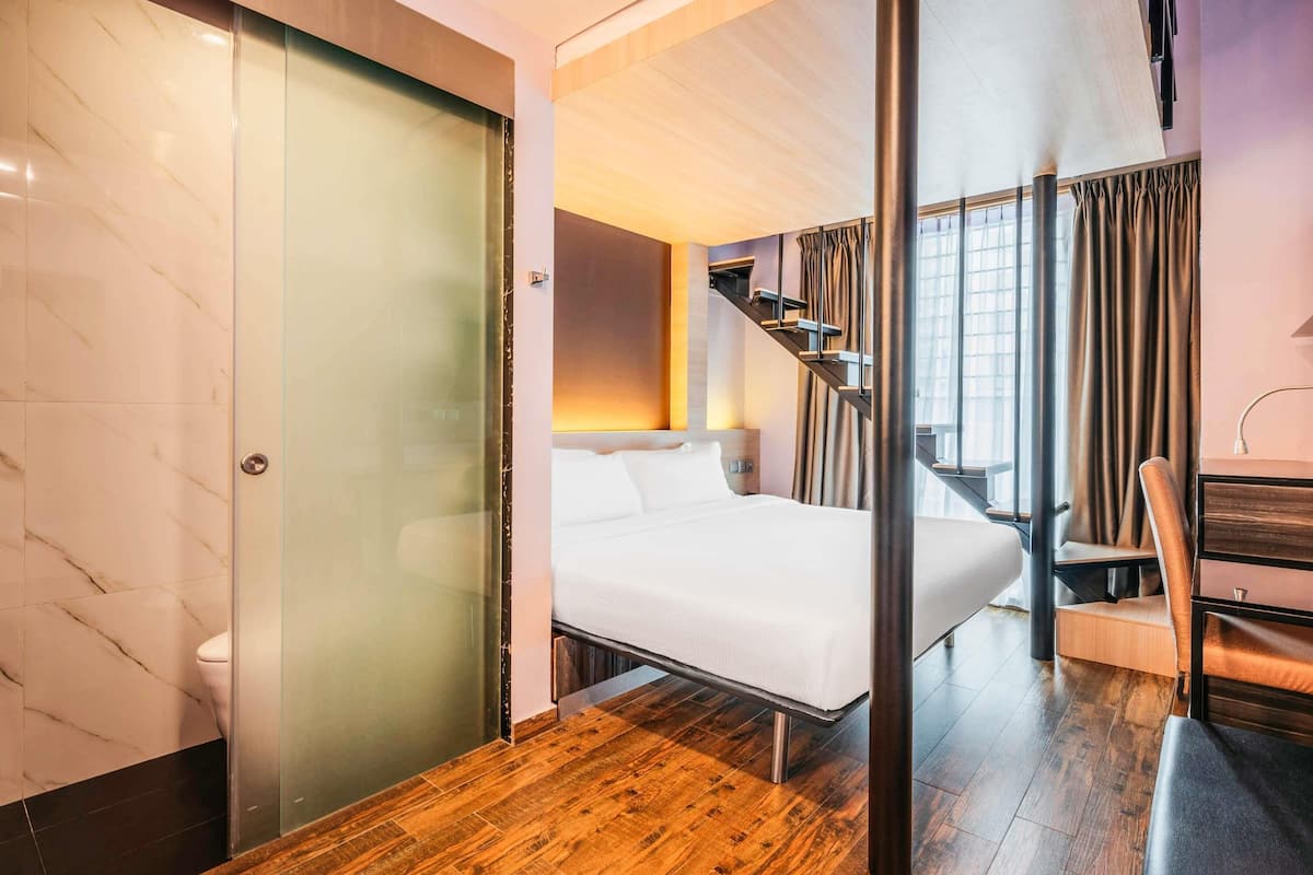 Une chambre d’hôtel moderne équipée d’un lit, d’un bureau et d’un escalier.