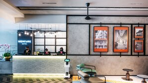 Un vestíbulo moderno de hotel con mostrador de recepción, quiosco digital y zona de estar.