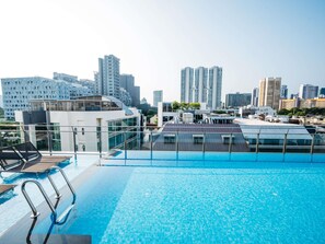 Una piscina infinita en la azotea con un horizonte urbano de fondo.