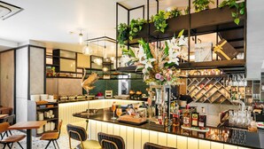 Zona de bar con mostrador, taburetes y una variedad de botellas y copas.