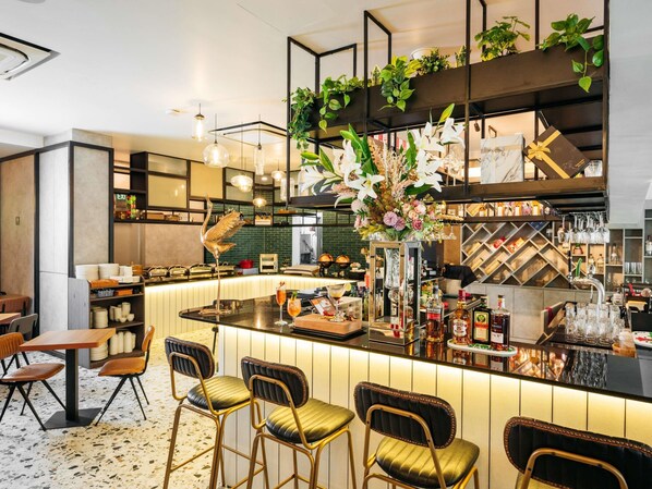 Zona de bar con mostrador, taburetes y una variedad de botellas y copas.
