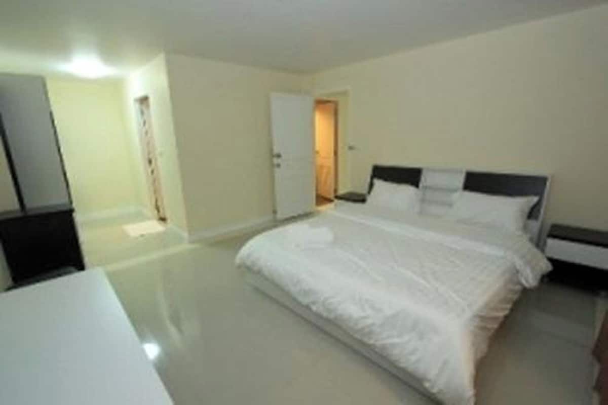 Una habitación de hotel con una cama, mesitas de noche y una puerta que da a otra habitación.