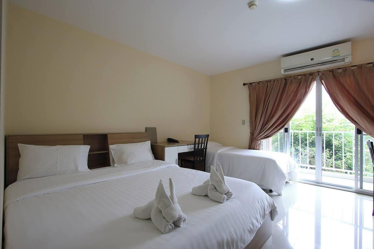 Una habitación de hotel con dos camas, un escritorio y un equipo de aire acondicionado.
